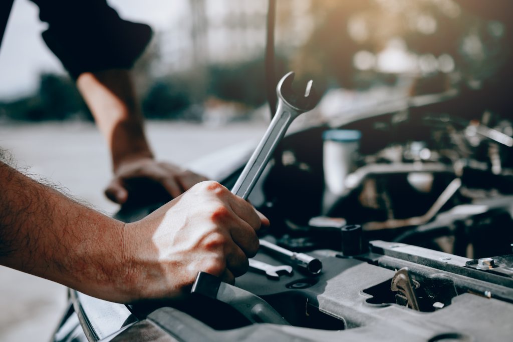  Le mécanicien automobile tient une clé prête à vérifier le moteur et l'entretien.